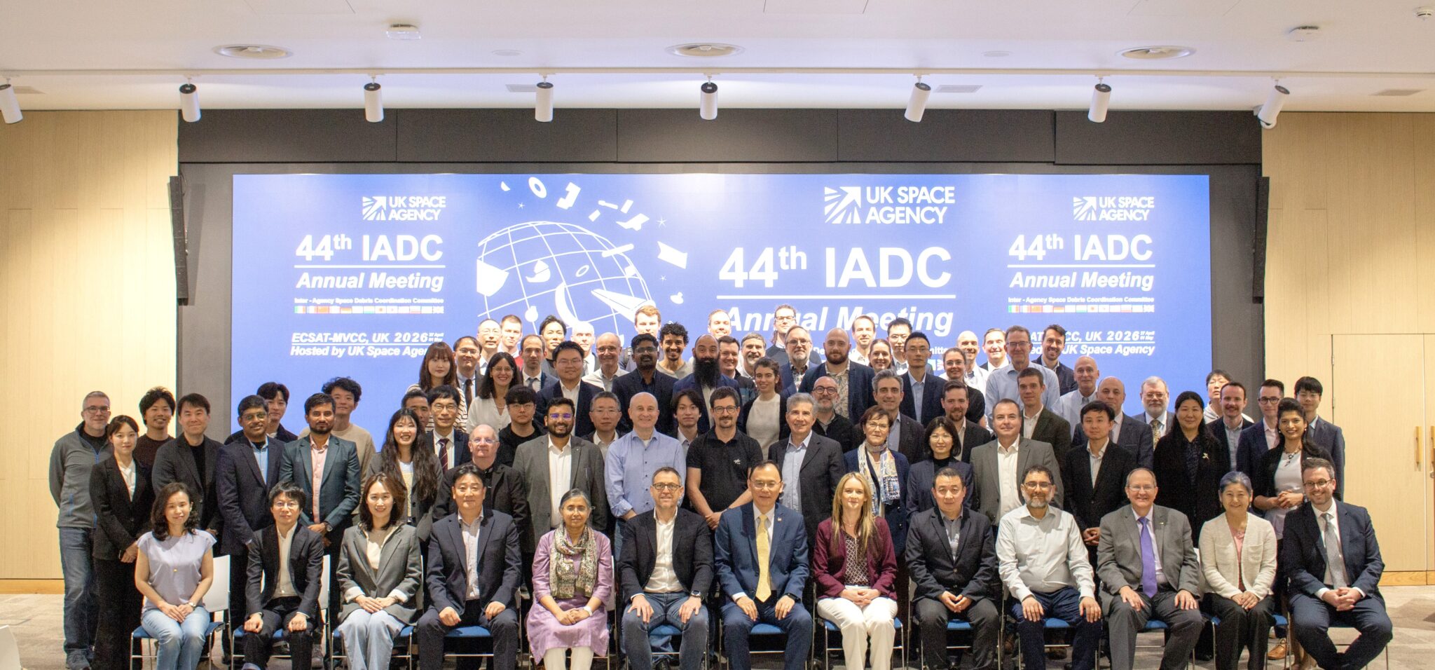 The IADC Committee standing and sitting in front of a title board at the 44th Annual Meeting, Harwell Campus, UK.