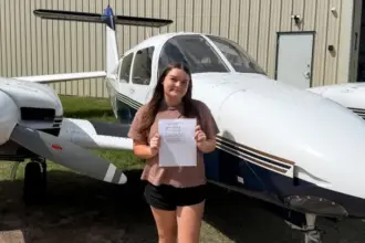 Emily Shelton standing in front of two aircrafts holding a piece of paper.