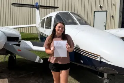 Emily Shelton standing in front of two aircrafts holding a piece of paper.