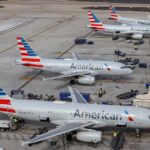Four American Airlines A320 parked on the gates of Phoenix Sky Harbour International Airport. The aircraft all have the same white body with an American flag tail.