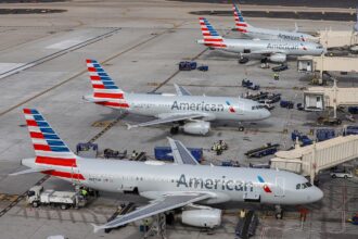 Four American Airlines A320 parked on the gates of Phoenix Sky Harbour International Airport. The aircraft all have the same white body with an American flag tail.