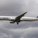 A Porter Airlines Embraer 195-E2 flying under a very cloudy and grey sky. The aircraft's livery is almost entirely white with a dark blue tail.