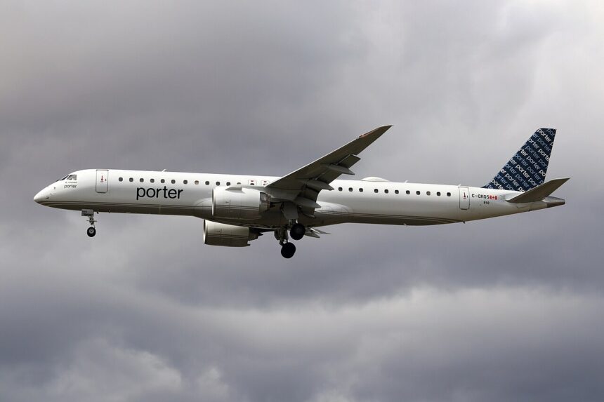 A Porter Airlines Embraer 195-E2 flying under a very cloudy and grey sky. The aircraft's livery is almost entirely white with a dark blue tail.