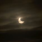 Image shows a dark sky with clouds and white sun and moon shape from 2011 solar eclipse