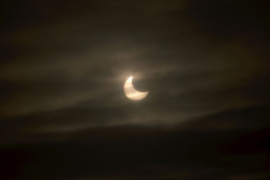 Image shows a dark sky with clouds and white sun and moon shape from 2011 solar eclipse