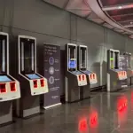 A line of EES kiosks with a large sign that instructs passengers of the registration process.