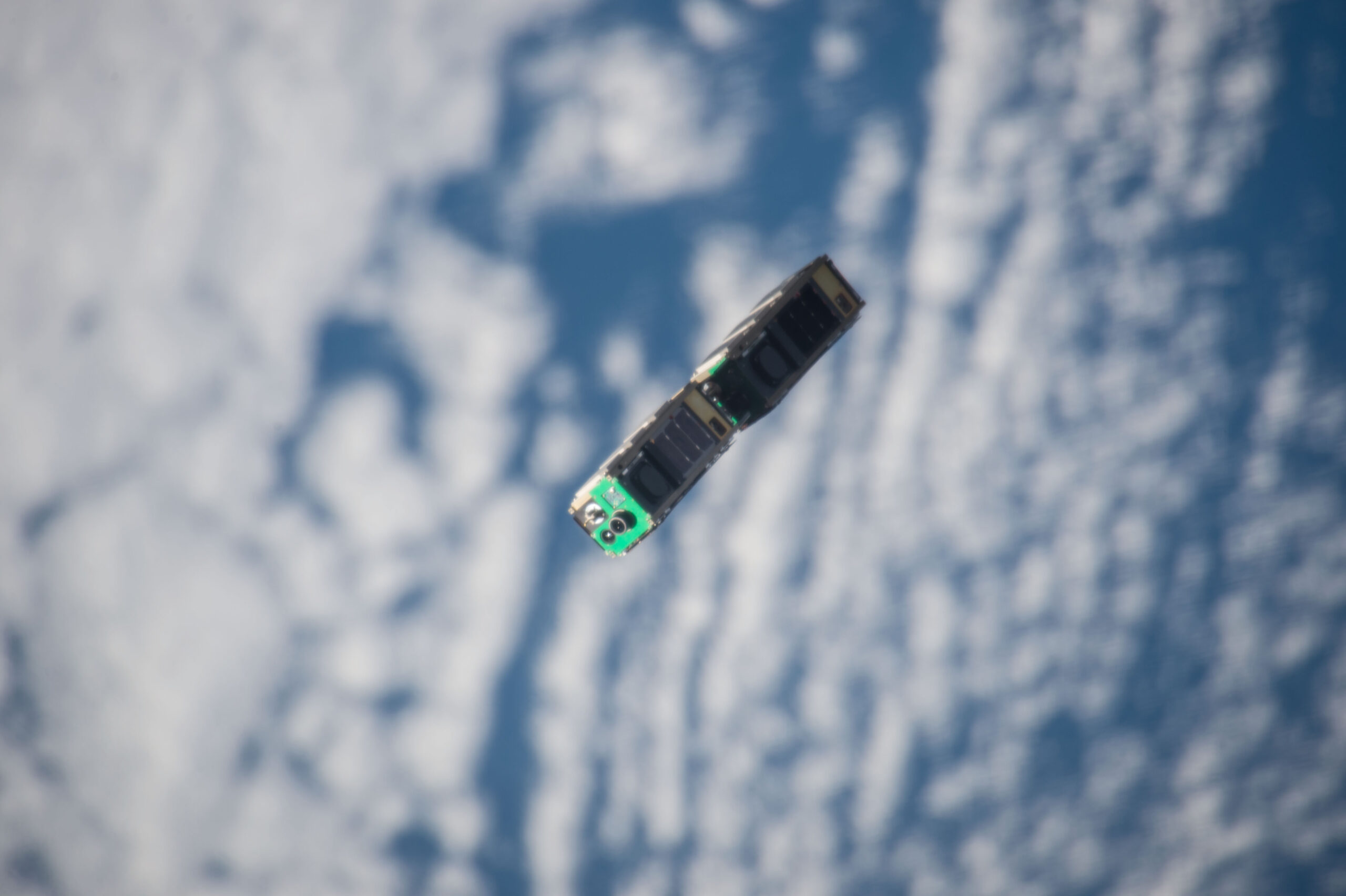 Two of Spire’s LEMUR-2 satellites – small, blue cuboidal objects – seen high above the Earth’s surface after being jettisoned from their launch vehicle.