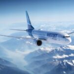 An WestJet Boeing 737-8 MAX aircraft flying above rocky mountains