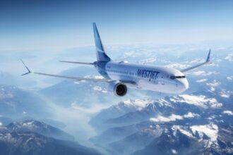 An WestJet Boeing 737-8 MAX aircraft flying above rocky mountains