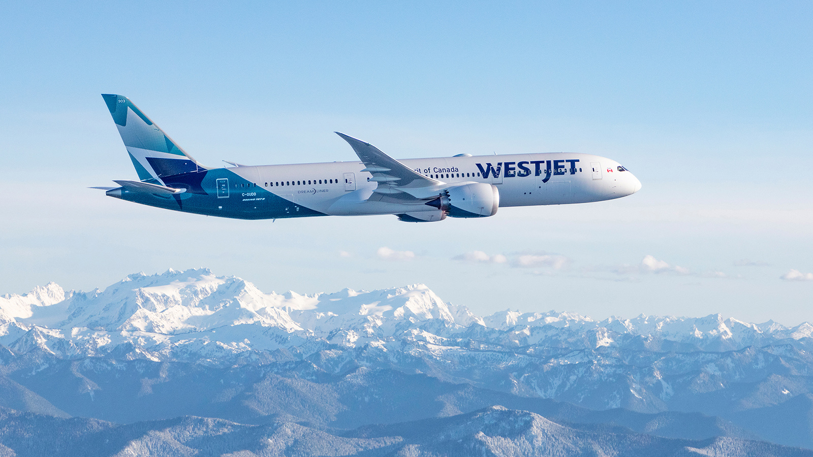 An WestJet Boeing 787-9 Dreamliner aircraft flying over rocky mountains
