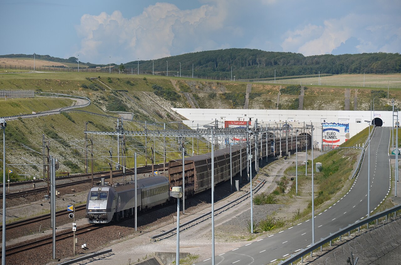 A Class 9705 freight train pulling road vehicle cars exits the Channel Tunnel at Coquelles.