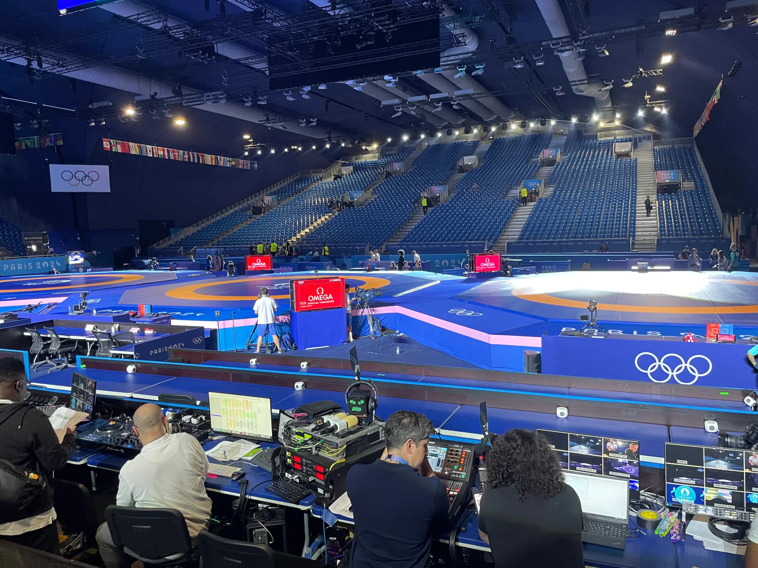 Ofcom staff sit at banks of broadcasting equipment inside a sports arena to assist French telecommunications regulators at the Paris 2024 Olympics.