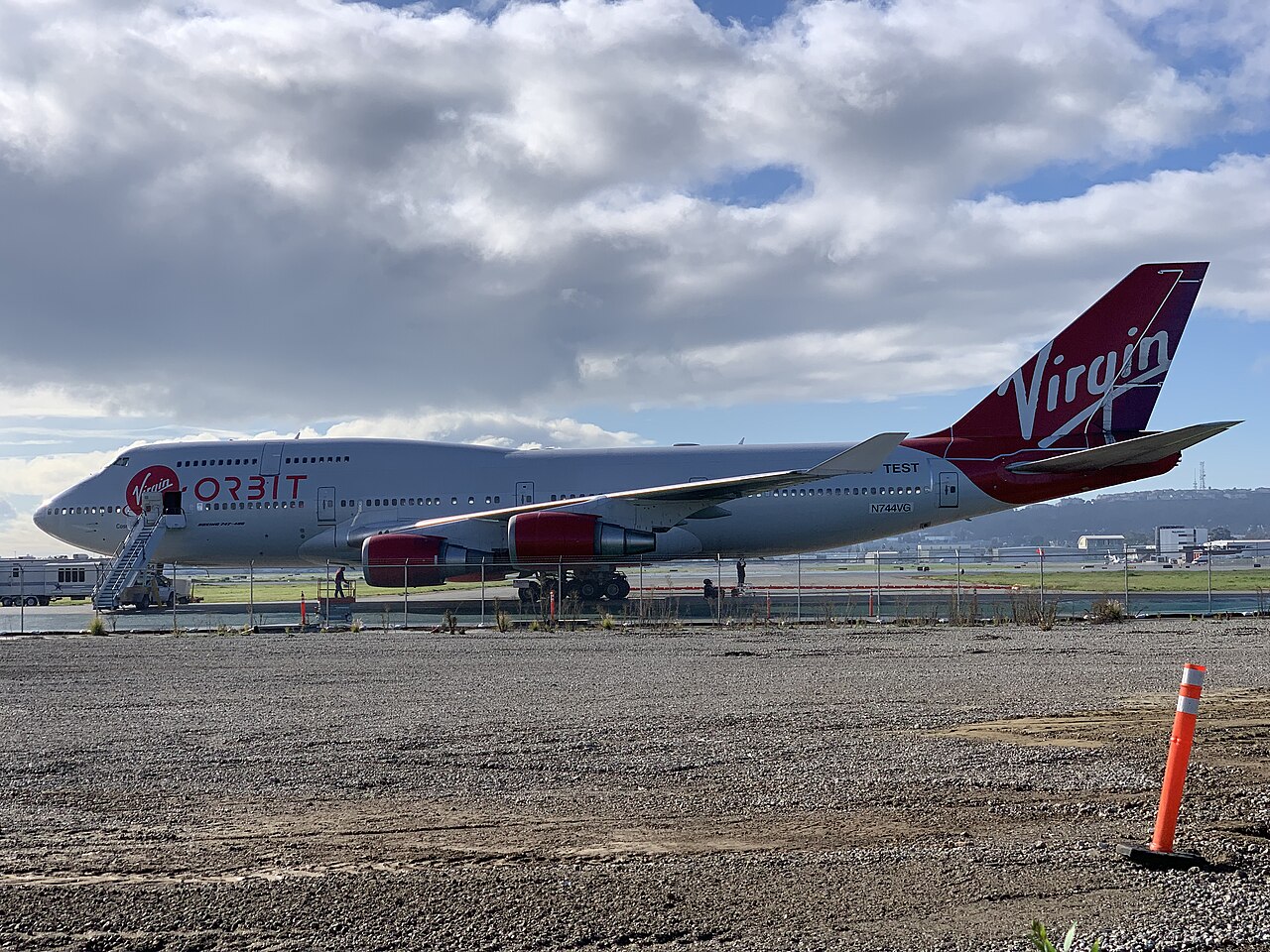 A white Virgin Orbit Boeing 747 with a large Virgin Orbit logo on the side, on the ground having released its rocket payload in flight.