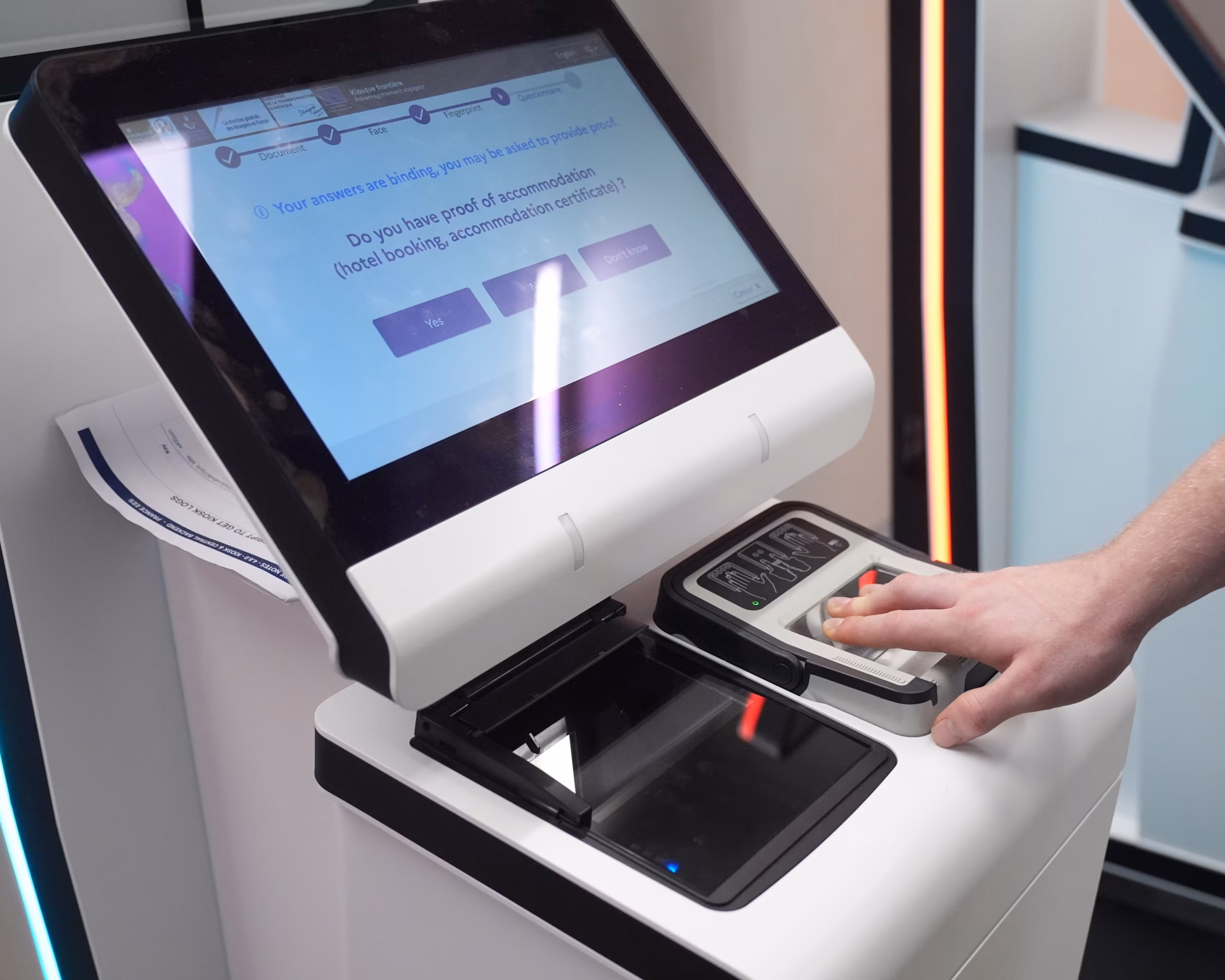 A EES machine with a passenger's hand on the fingerprint scanner.