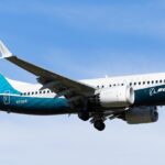 A full-length side view of Boeing's 737 MAX 7 (registration N7201S) in the air with its landing gear still extended.