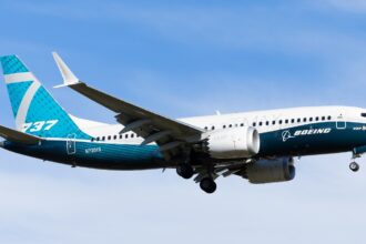 A full-length side view of Boeing's 737 MAX 7 (registration N7201S) in the air with its landing gear still extended.