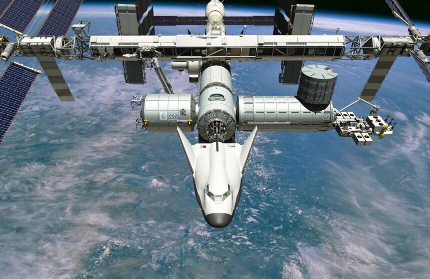 Artist’s impression of the Dream Chaser spaceplane, which has a futuristic, streamlined, bulbous aircraft shape, docked to the ISS, a large satellite with many gantries and solar panels, orbiting above the ocean on Earth.