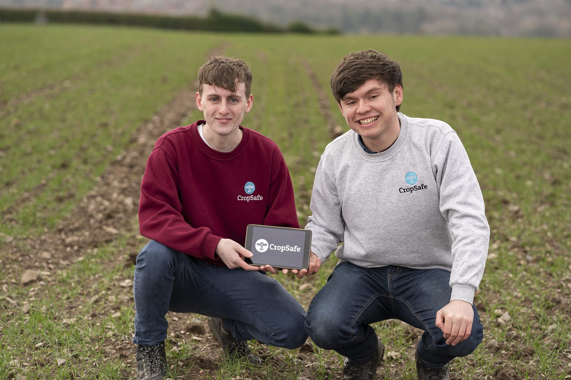 John McElhone and Micheál McLaughlin, crouching in a field with an iPad displaying their logo, are the team behind CropSafe.