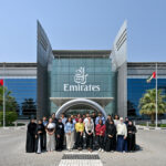 Students taking part in the materials studio stand outside a glass emirates building.