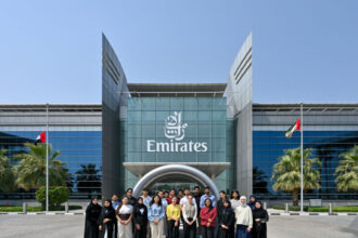 Students taking part in the materials studio stand outside a glass emirates building.