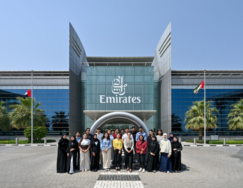 Students taking part in the materials studio stand outside a glass emirates building.