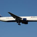 A Delta Air Lines Boeing 767-300ER (registration N160DL) on approach with landing gear extended, featuring the airline's signature white, blue, and red livery with the widget logo on the tail and "DELTA" titles on the fuselage, set against a clear blue sky.