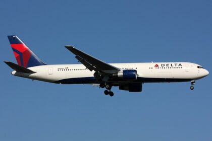 A Delta Air Lines Boeing 767-300ER (registration N160DL) on approach with landing gear extended, featuring the airline's signature white, blue, and red livery with the widget logo on the tail and "DELTA" titles on the fuselage, set against a clear blue sky.