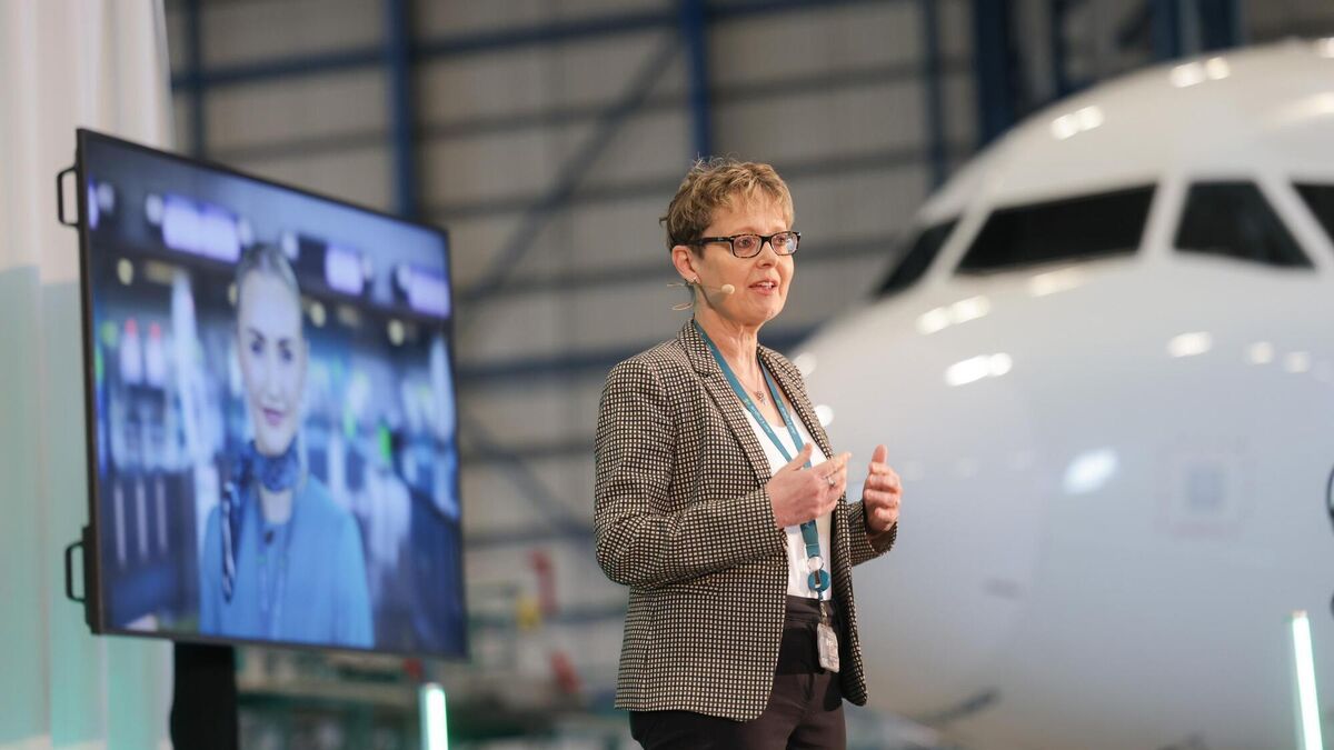 Lynne Embleton, CEO, Aer Lingus, pictured at Dublin Airport, delivering a talk against a screen featuring an Aer Lingus cabin crew member.