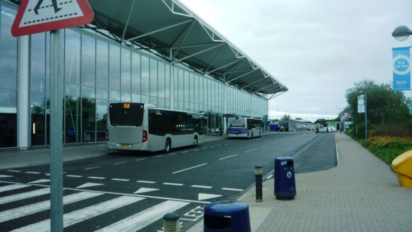 A front view of Bristol Airport's terminal with a blue afternoon sky backdrop and a zebra road crossing at the front