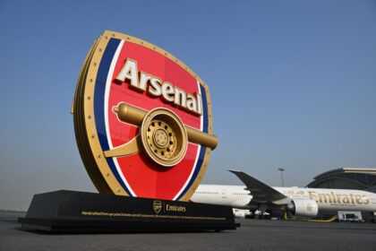 Photograph depicting 3D Arsenal logo positioned in front of an Emirates aircraft on the runway.