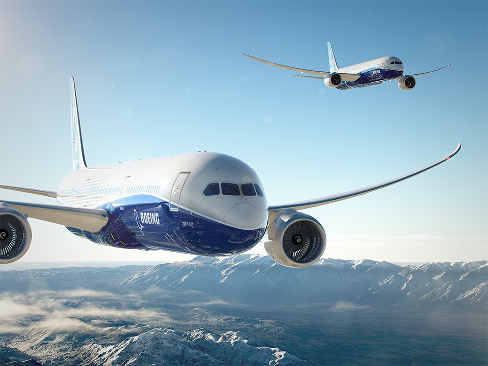 A promotional image of two Boeing 787s flying over an a mountain range against a blue sky.