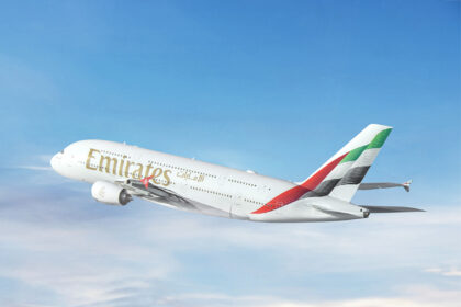 An Emirates Airbus A380 aircraft featuring the flag colors of the UAE on its tail and photographed on its left-hand side
