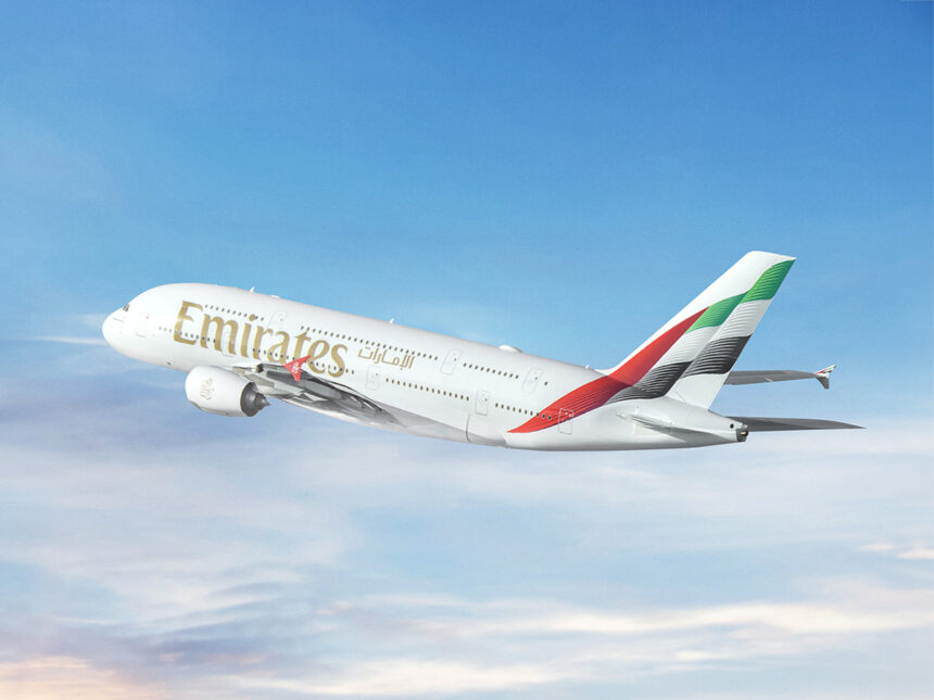 An Emirates Airbus A380 aircraft featuring the flag colors of the UAE on its tail and photographed on its left-hand side