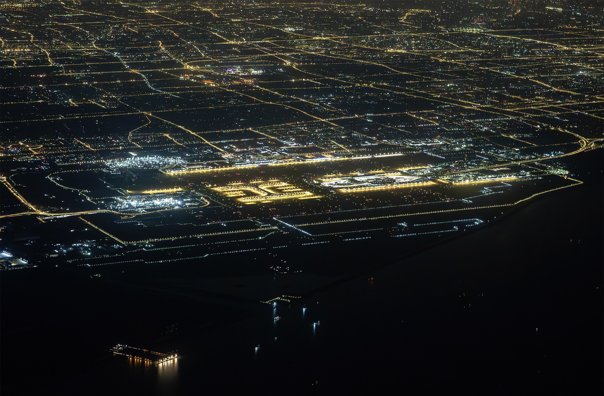 Shanghai Pudong International Airport (PVG) at night. The airport terminals are lit up against a dark city backdrop.