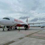 An Air India Airbus A320 parked on a runway in front of a cloudy sky.