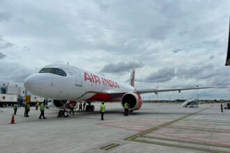 An Air India Airbus A320 parked on a runway in front of a cloudy sky.
