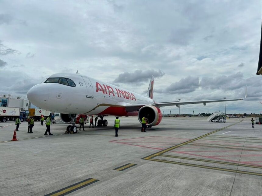 An Air India Airbus A320 parked on a runway in front of a cloudy sky.