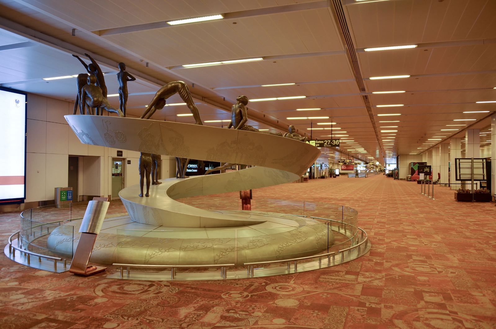 A terminal building at Indira Gandhi International Airport, Delhi (DEL). A water feature is seen in front of a hallway with an orange carpet.