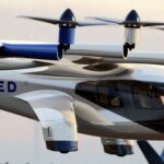 A blue and white Archer Midnight aircraft hovering above the ground in front of a sunset. It is painted in the livery of United Airlines.
