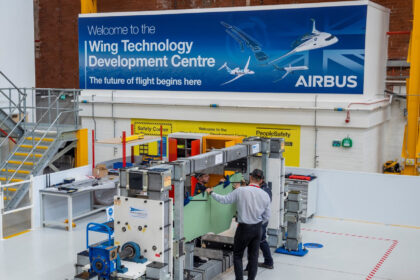 Airbus employees at the Wing Technology Development Centre in Filton, UK. They are seen working on a production line, in front of a blue sign.