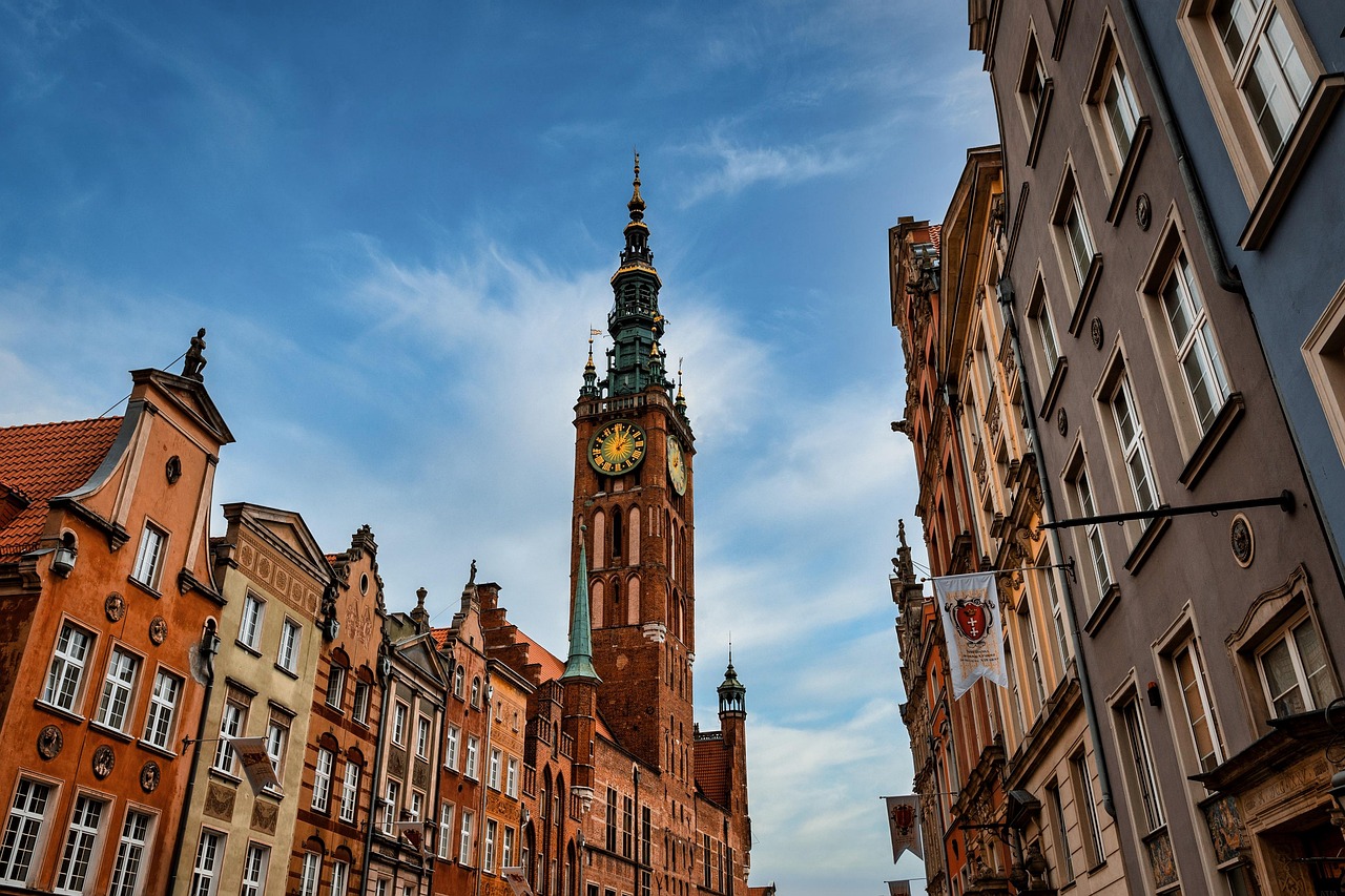 A view looking up at a church spire in the city of Gdansk, Poland. The sky behind is dark blue and cloudy.