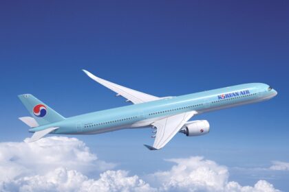 A blue and white Korean Air jet flying upwards in front of a cloudy sky.