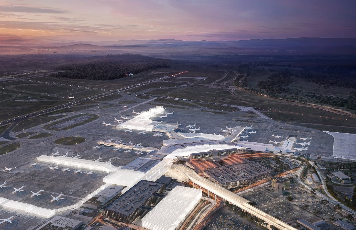 Melbourne airport at sunset, the terminals and runways are lit up, and a cloudy sky can be seen in the background.