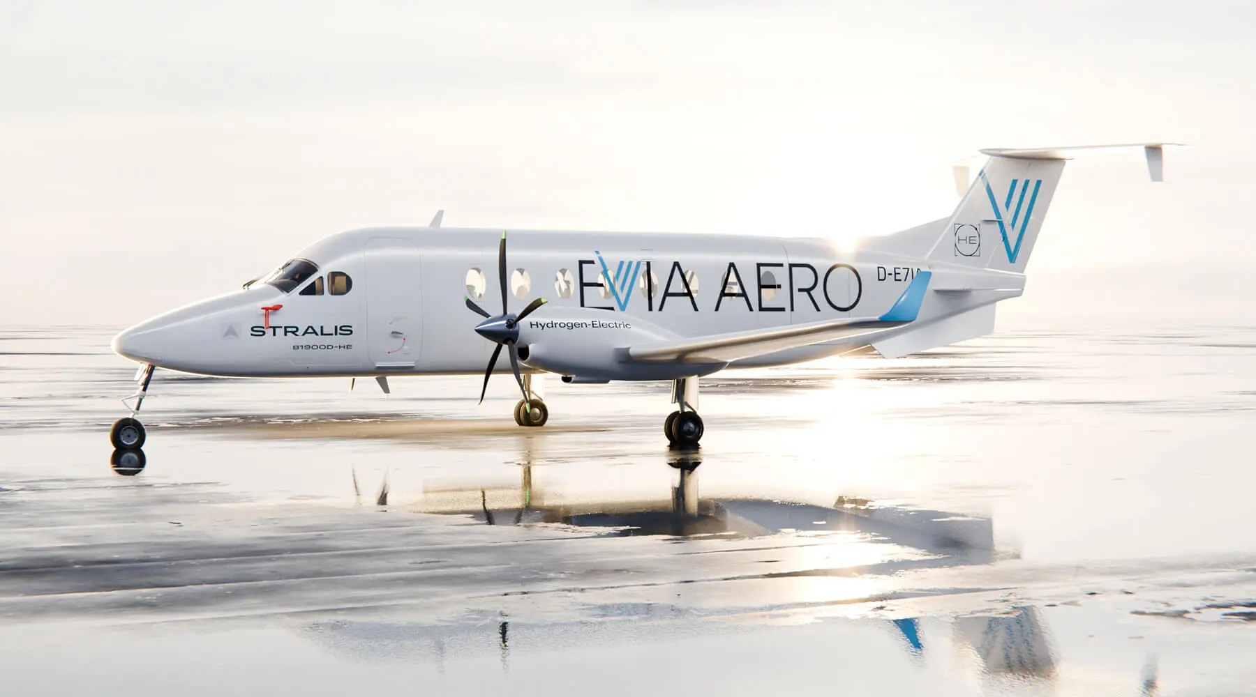 A white Stralis jet with the Evia Aero name and logo printed on the side. The jet is sat on a damp runway at sunrise.
