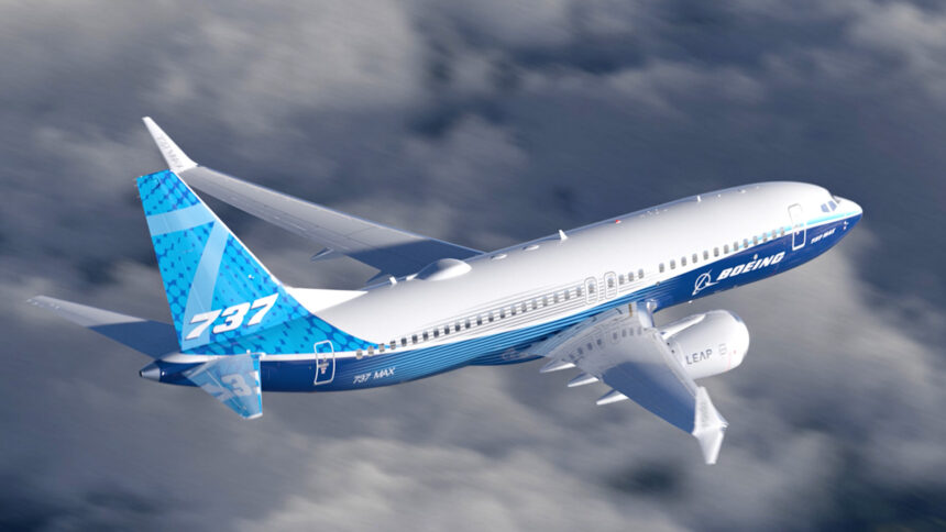 A blue and white Boeing 737 jet flying over a cloudy sky.