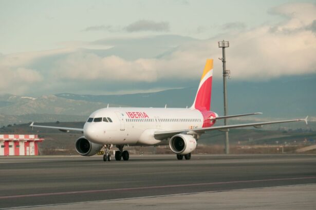 An Iberia A320 sitting on tarmac with a cloudy sky backdrop.