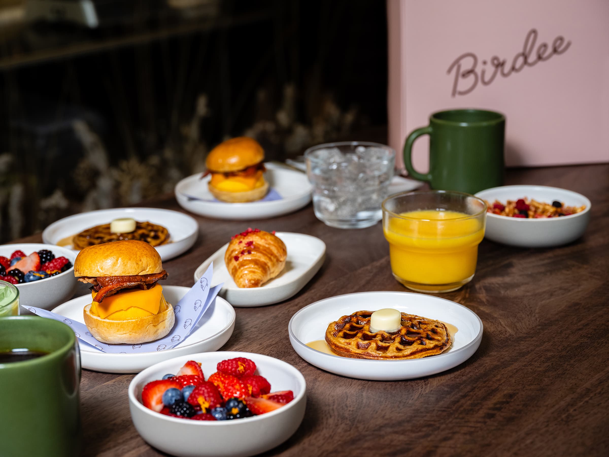 Various breakfast items on a table with cups of coffee and a Birdee menu in the background.