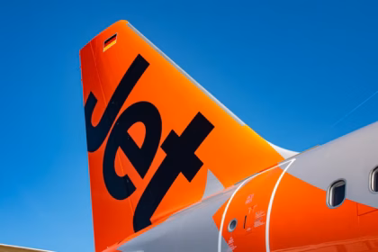 Bold orange rear of a Jetstar A321, featuring the company logo. The plane is against a sunny blue sky background.