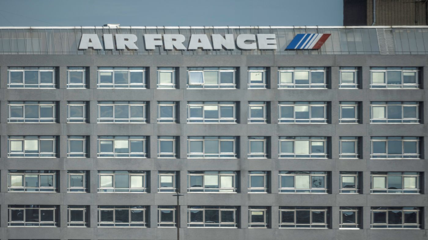 A front view of Air France building based in Charles De Gaulle Airport the building is built with grey concrete and feature an white and blue Air France logo at the top with a clear blue sky backdrop