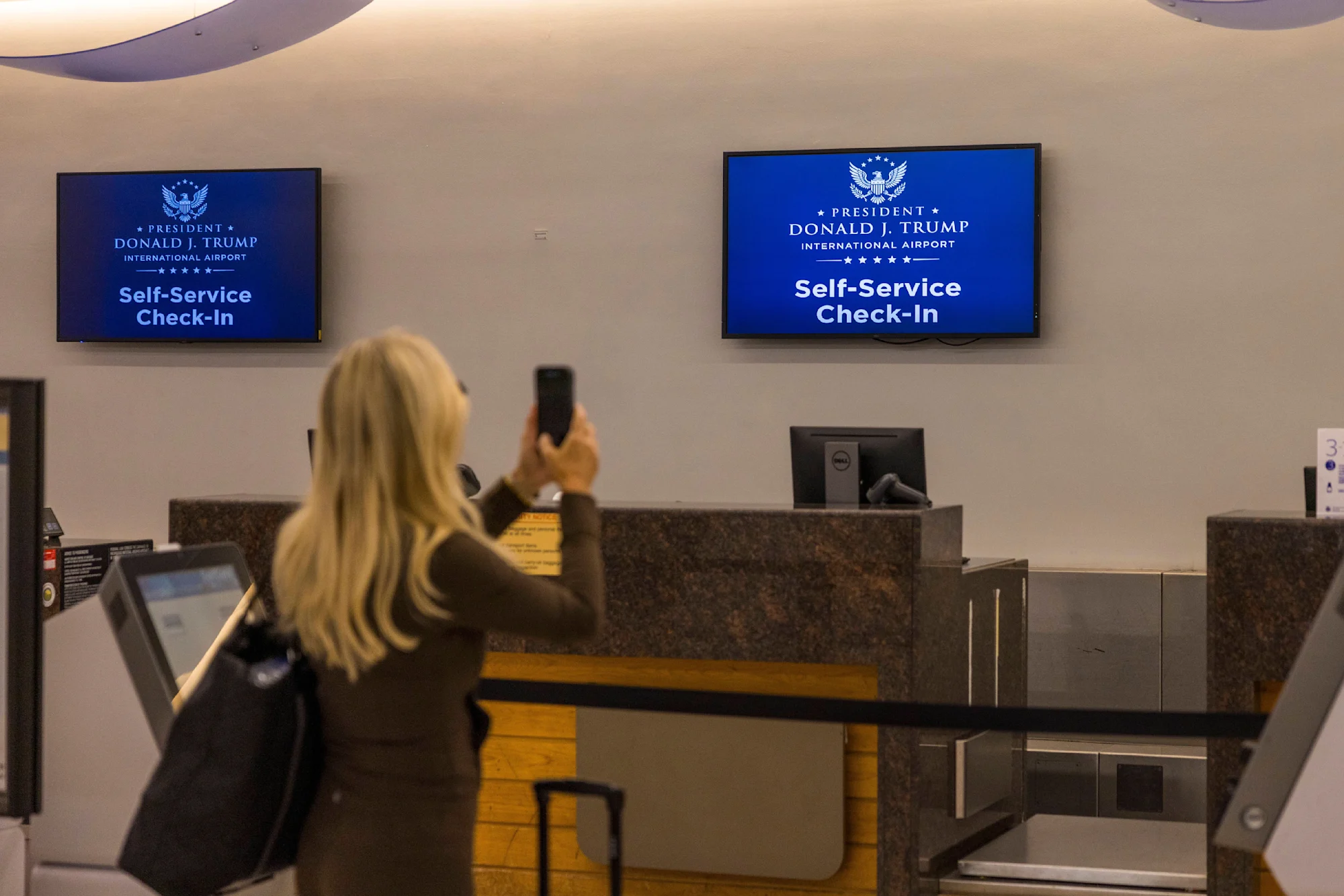 A passenger takes a photo on her phone of a check-in sign which reads: 